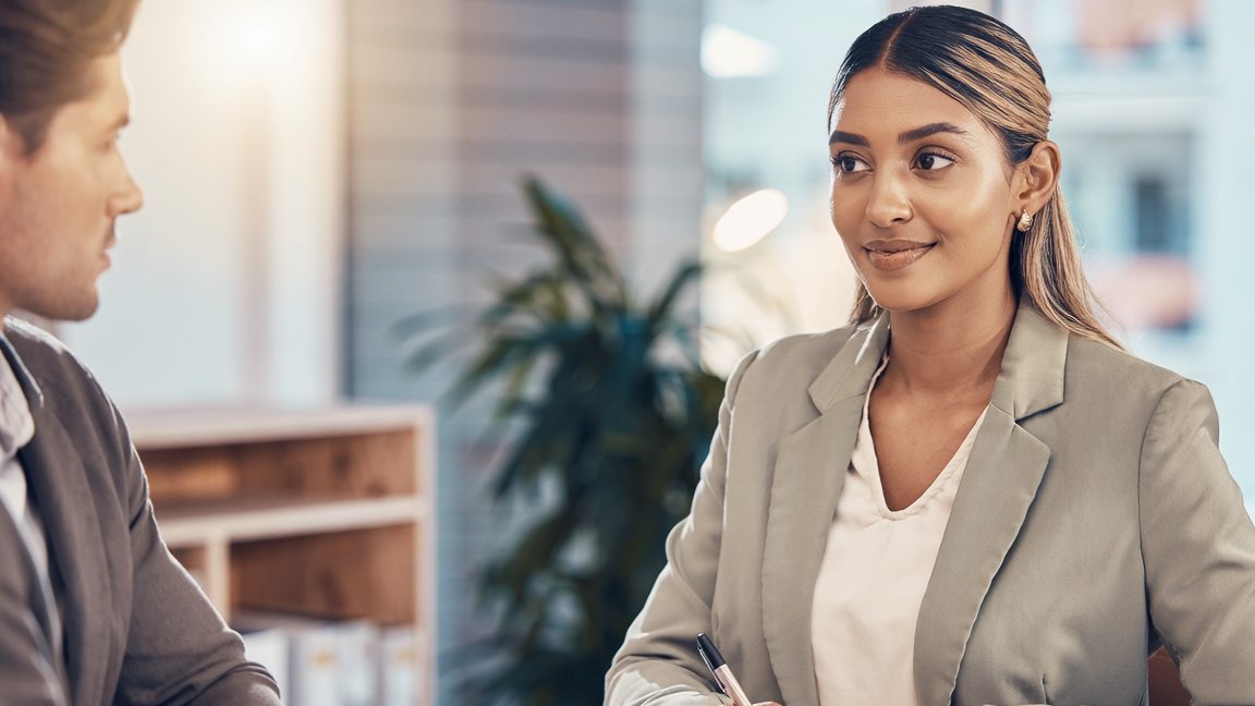 Mujer sonriendo mientras conversa con un colega en una oficina — inteligencia emocional en el trabajo