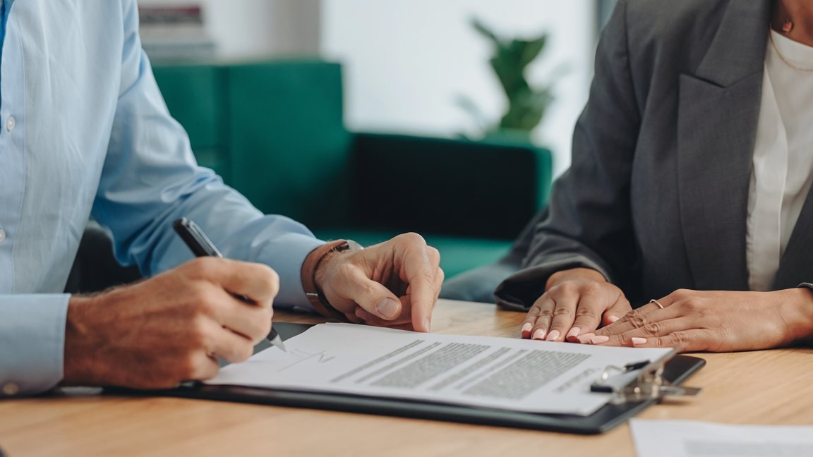 Dos personas firmando un documento sobre un escritorio — test de integridad laboral